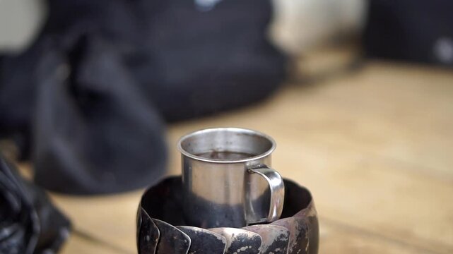Close-up of a mini metal cup for boiling water or coffee with an aesthetic blurred background.
