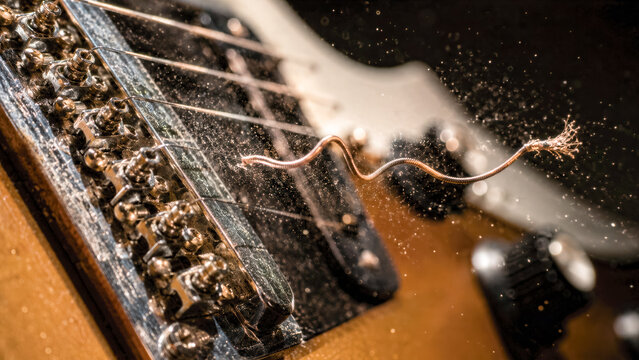 Close-up of a guitar copper string snapping mid-strum with the violent wave frozen in a perfect sinusoidal curve