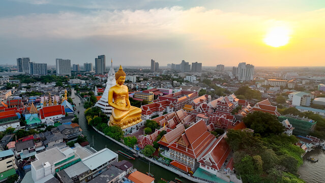 Spectacular panoramic aerial urban view of the giant golden Buddha statue and stupa at Wat Paknam Bhasicharoen with dramatic sky dusk sunbeams in Bangkok cityscape