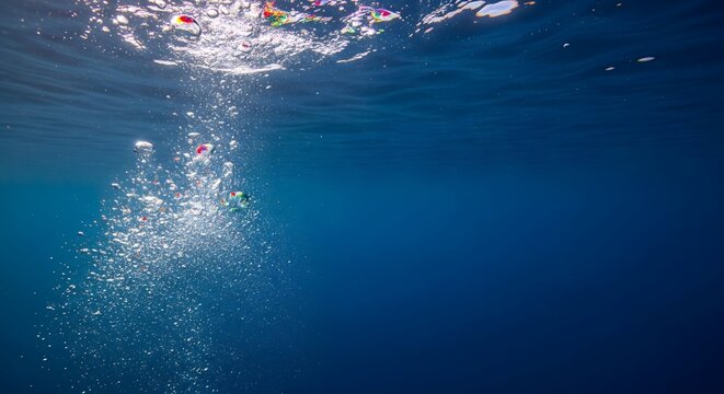 Air bubbles rising to the water surface in a deep blue ocean sea