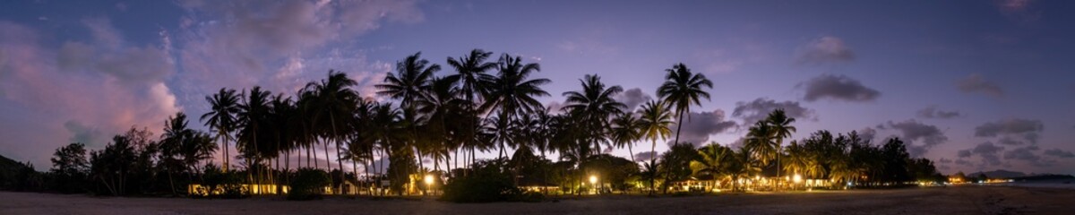 Fototapeta premium Dramatic panorama sky with cloud on twilight time at a beach with coconut palm trees.