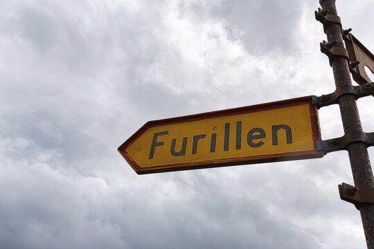 Yellow sign with inscription Furillen, signpost made of rusted iron, cloudy sky, L&auml;rbro, Furilden nature reserve and bird sanctuary, Furillen Island, near Gotland, Sweden
