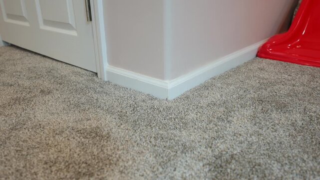 Gray carpet flooring installed inside modern residential home featuring white baseboards, interior door, and clean renovated room corner
