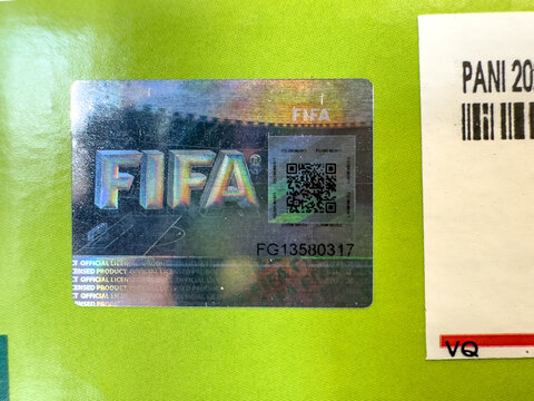 Calgary, Alberta, Canada. June 1, 2026. Official FIFA holographic security sticker with QR code on a bright green surface, macro view.