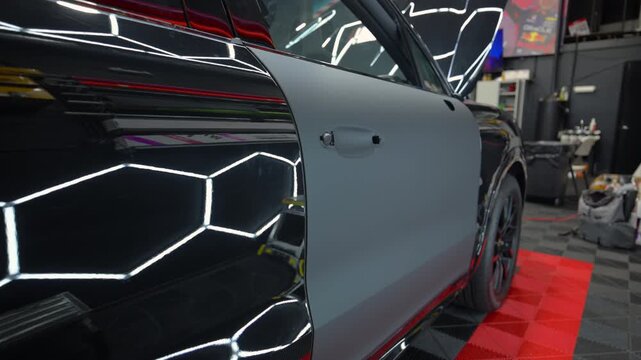 Close up view of a car installed protective vinyl film inside automotive detailing studio during luxury car customization and paint protection service