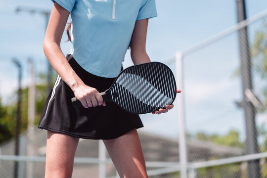 Pickleball sports player resting on outdoor court. Tired female athlete holding paddle and bending knees during fitness training.