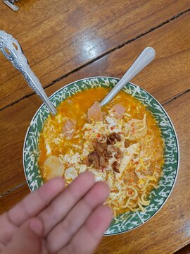 Spicy Indonesian seblak with chicken feet, tofu, sausage, crackers, lime, and vegetables in chili broth