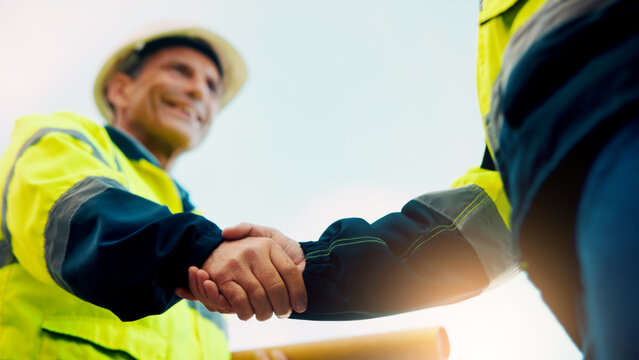 Contractor, construction or handshake with happy man for architecture partnership or deal together. Person, builder or civil engineer shaking hands with smile for building agreement in site low angle