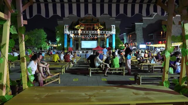 People Watching Traditional Outdoor Stage Performance in a Night Square