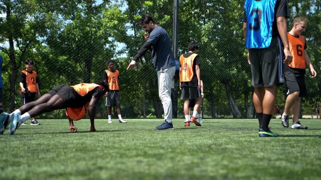 Soccer coach leading a practical training drill with players on an outdoor football field, focusing on teamwork, positioning, and game strategy development