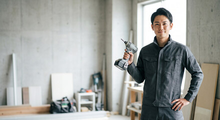 建築現場で電動ドライバーを持つ作業着姿の男性