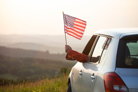 Man in the car holding a waving american USA flag.