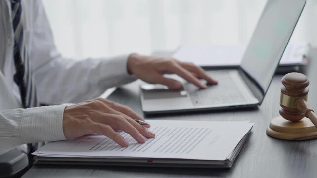 Lawyer checking documents and typing on laptop