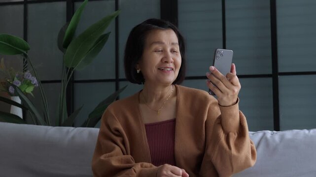 Asian mature woman using smartphone talking by open speakerphone