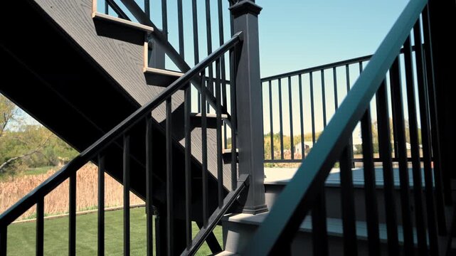 Modern elevated backyard deck attached to suburban house featuring black metal railings and outdoor stairs in residential neighborhood