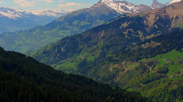 Aerial view of the majestic snow-capped peaks and lush green valleys of the Swiss Alps in Grisons, Switzerland.