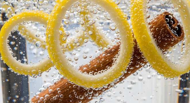 Refreshing drink with lemon swirls and cinnamon stick, bubbles and fizz creating abstract pattern, close up beverage.