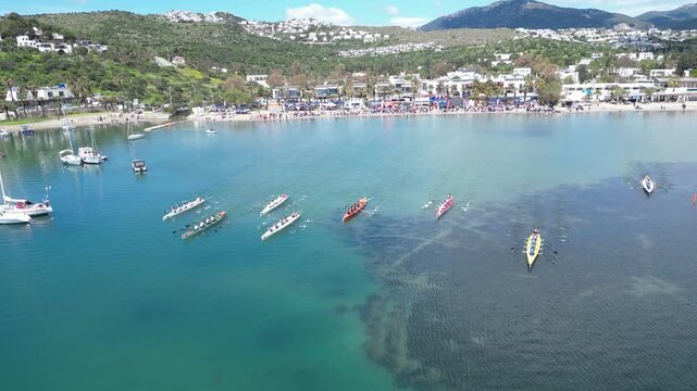 Aerial View of Professional Rowing Teams Competing in a Regatta near Scenic Coastal Town with Mountains. High quality 4k footage
