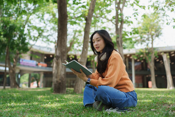 Fototapeta premium Young woman learning outdoors reading book on campus