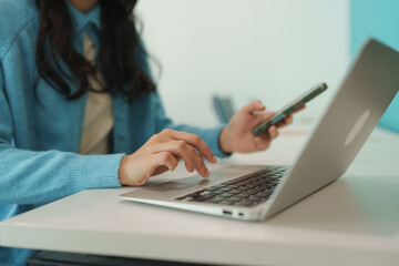 Fototapeta premium Woman working on laptop and checking phone