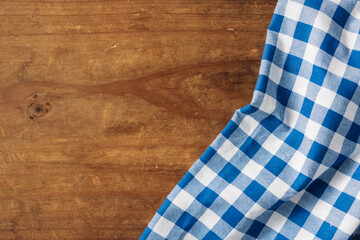 Obraz premium Blue and White Checkered Tablecloth on Rustic Wooden Surface