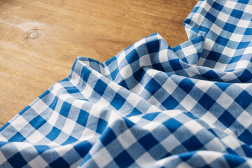 Obraz premium Blue and White Checked Fabric on Wooden Surface for Textiles Background