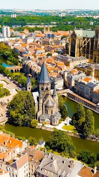Vertical video. Metz, France. Temple Neuf, a Neo-Romanesque Protestant church with a conical spire, Drone footage over the Moselle River on a bright summer day. Drone footage. Rich colors