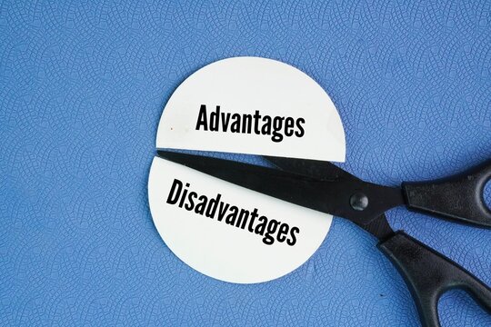 Scissors and two pieces of paper are separated by different words Disadvantage and Advantages. the positive and negative aspects of a choice, situation, or tool. Advantages provide a benefit, gain