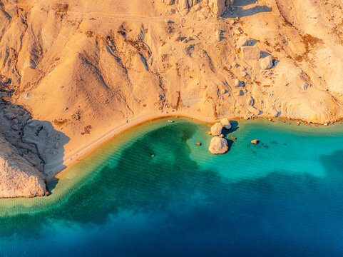Rucica beach in Metajna on Pag island curved shoreline, crystal-clear turquoise sea, sunlit barren terrain and rocky Adriatic sea