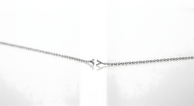 Broken silver chain necklace separated on a white reflective surface