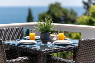 Fototapeta premium Breakfast on wicker table on sunny terrace balcony with ocean sea view morning furniture