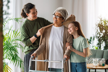 Naklejka premium Happy Multigenerational Family Supporting Senior Woman with Walker at Home