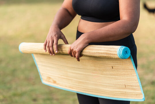 Woman rolling a straw yoga mat outdoors after the yoga session