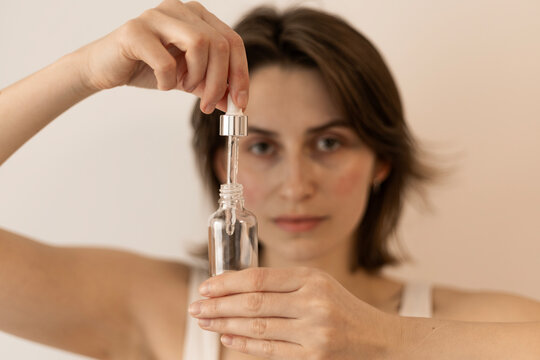 Woman holding a dropper bottle of clear serum for natural skinca