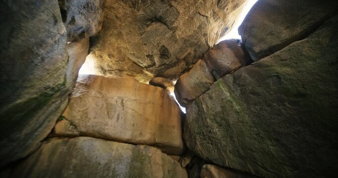 Steady cam through rocky structure interior with sunlight peeking through