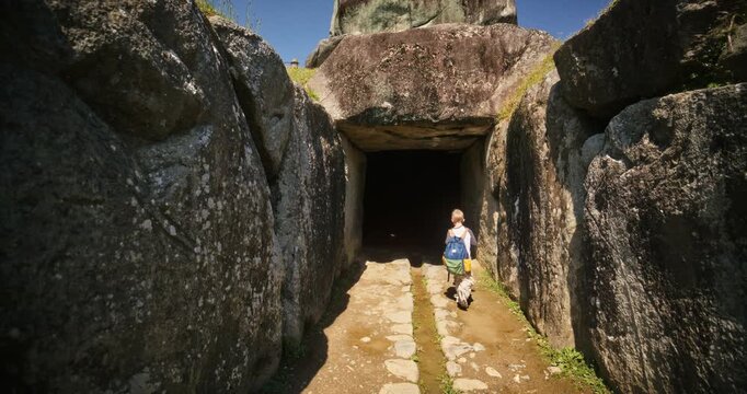 Megalithic stone chamber and passageway, steady cam following little boy with backpack inside