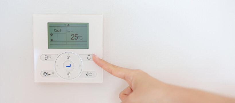 operating and adjusting Air conditioner temperature by remote control in home. Hand holding remote control and setting comfortable temperature on climate system in office or apartment. hot and cool