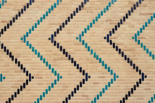 Decorative brickwork with turquoise and dark blue glazed tiles forming geometric patterns on Bibi Khanum Mosque in Samarkand. Tiles texture, pattern, background.