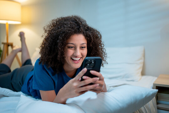 Attractive Latina woman using mobile phone at night at home. 