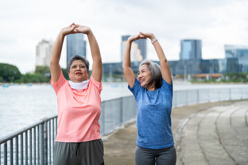 Obraz premium Two Asian senior women warm up body and exercise outdoor in modern city. 