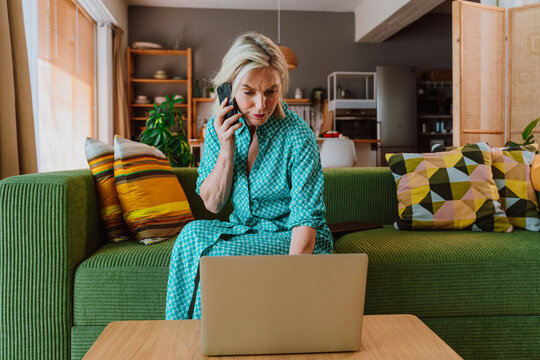 Senior woman using laptop on sofa in modern living room