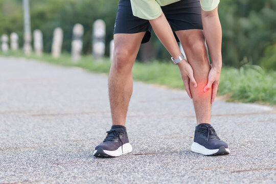 Athletic man having leg ache and shin pain while jogging in the park. Male runner with sports injuries, shin splints or stress fracture during training. Medial Tibial Stress Syndrome and Inflammation