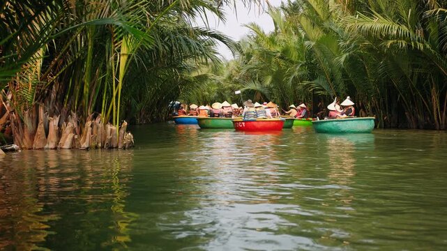 Tourists traveling in vietnam basket boats on a river through a lush coconut palm forest in hoi an, vietnam