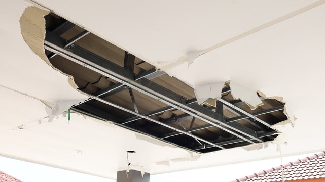 Damaged ceiling panels. Plaster ceiling with damaged cracks and large holes from roof water leak with copy space and selective focus.