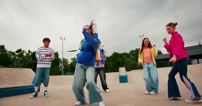 Group of energetic teenagers dancing hip hop in a skatepark