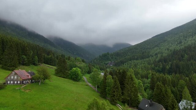 Aerial view of a misty mountain valley with spruce forest and scattered cottages in Krkono&scaron;e Czech Republic