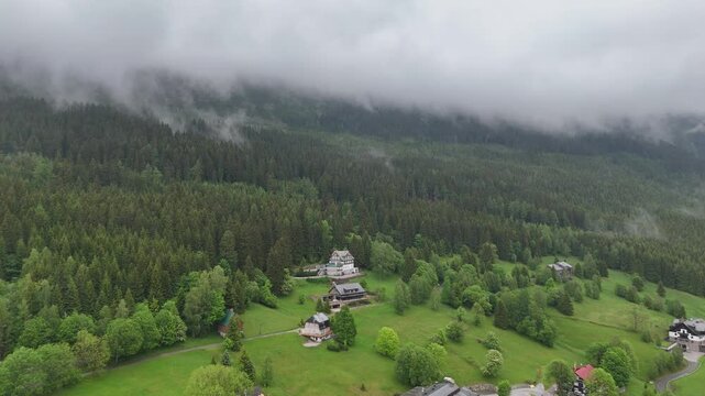 Aerial view of a misty mountain valley with spruce forest and scattered cottages in Krkono&scaron;e Czech Republic