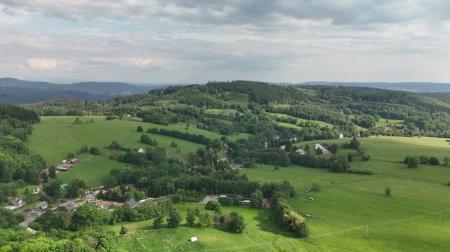 Rolling green pastures and scattered houses among hazy layered ridges
