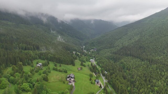 Aerial view of a misty mountain valley with spruce forest and scattered cottages in Krkono&scaron;e Czech Republic