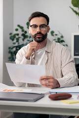 Obraz premium Young businessman analyzing financial document, planning strategy in office